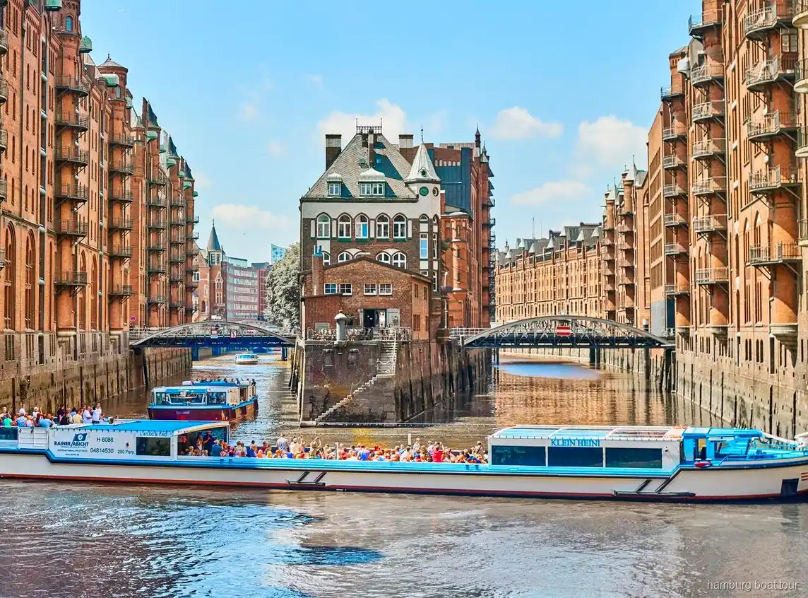 Passatgers a la coberta oberta d'un vaixell de creuer pel port i Speicherstadt de Hamburg
