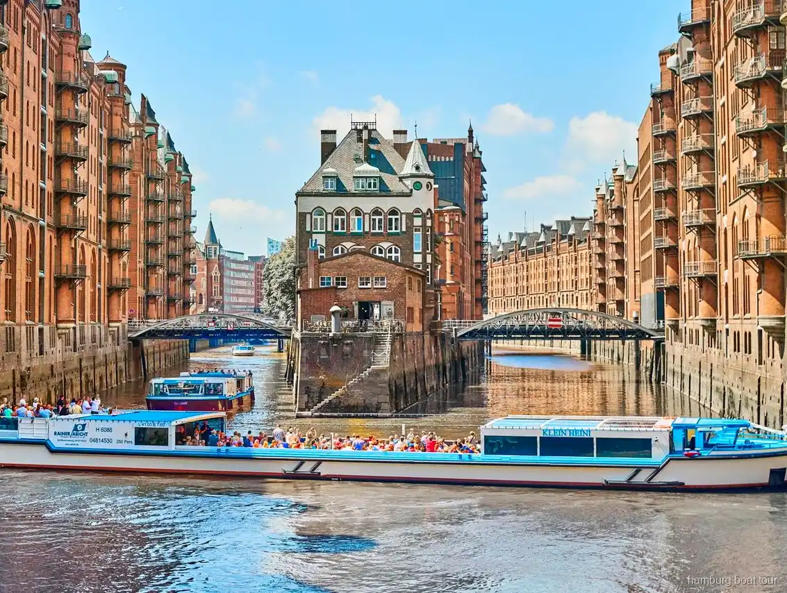 Passagerer på det åbne dæk af en havnerundfart med Speicherstadt i Hamborg